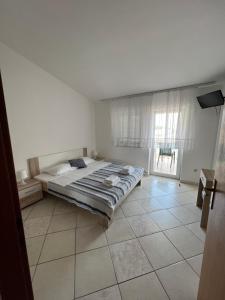 een witte slaapkamer met een bed en een raam bij Apartments Kulic in Tisno