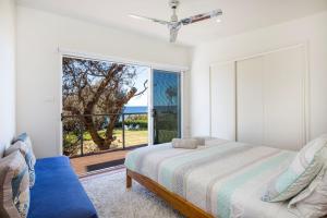 a bedroom with a bed and a large window at Aqua Beachfront - Pet Friendly - 2 Mins Walk to Beach in Culburra Beach