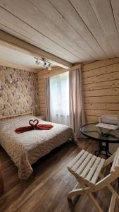 a bedroom with a bed and a table and a chair at Guest House Firebird in Belokurikha