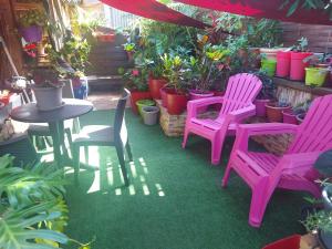 um grupo de cadeiras cor-de-rosa e uma mesa e plantas em Ti Coin Des hauts de saint joseph 974 em Saint-Joseph