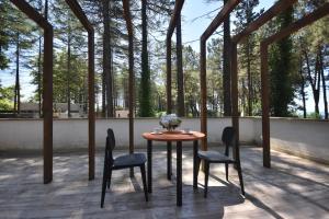 einen Tisch und Stühle auf einer Terrasse mit Bäumen in der Unterkunft Pine Aparthotel in Shekhvetili