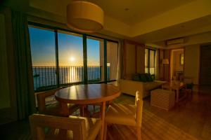 Moon Ocean Ginowan Hotel & Residence في غينوان: غرفة معيشة مع طاولة وإطلالة على المحيط