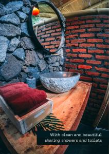 a bathroom with a sink and a mirror and a rock wall at Desa Eko in Munduk