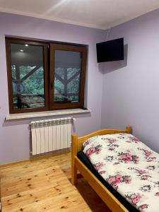 a bedroom with a bed and a tv on the wall at Agroturystyka Nad Czarnym in Giby