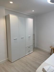 Apartamento Arena Benidorm في بنيدورم: غرفة نوم بيضاء مع خزانة بيضاء كبيرة