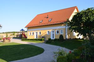 a yellow house with an orange roof and a driveway at Ferienhäuser Schneeberger 