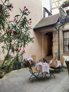 un patio con 2 mesas, sillas y un árbol en Hotel Saint-Martin, en Colmar