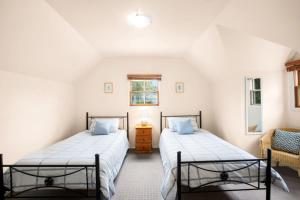 two beds in a room with white walls at Bunyip Cottage in Katoomba