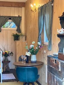 a room with a table with a blue chair and flowers at The Tiny Garage in Kampen