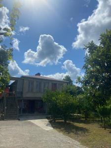 ein Haus mit Bäumen und einem blauen Himmel mit Wolken in der Unterkunft DEA in Sugdidi