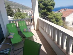 a balcony with green chairs and a view of the ocean at Apartments Eti in Bol