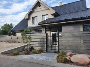 una casa con una puerta negra delante de ella en Kalvāni en Mērsrags