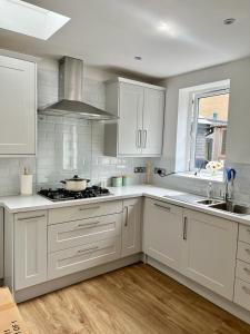 cocina con armarios blancos y fogones en Family home in Hampshire - Sleeps up to 9 people with 3 parking spaces, en Winchester