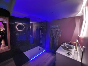 ein Bad mit einer Dusche mit blauer Beleuchtung in der Unterkunft Caen, Tu m'aimes - Suite Romantique in Caen