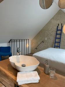 a bathroom with a white sink on a wooden table with a bed at MAISON SEIZE in Préaux