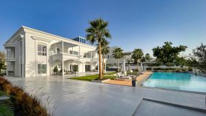 a large white house with a swimming pool in front of it at Villa Botanica-Exclusive 8-Bedroom Villa by Luxury Explorers' Collection in Dubai