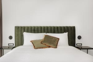 Cens Bronze Luxury Suites في يوانينا: غرفة نوم مع سرير أبيض مع اللوح الأمامي الأخضر