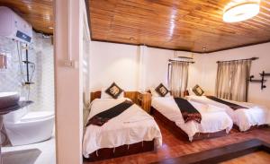 Habitación con 2 camas y baño con bañera. en Nammavong Guesthouse, en Luang Prabang