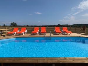 una fila de sillas y una piscina con sillas rojas en Le Chêne d’Or, en Marcheseuil