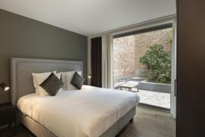 a bedroom with a large bed and a large window at Dukes' Apartments Grand Place - by Dukes' Hotel Collection in Bruges