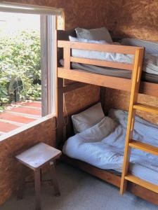 GUEST HOUSE NAGORIYA في هيكونا: غرفة مع سرير بطابقين ومقعد بجوار النافذة