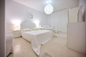 - une chambre blanche avec un lit blanc et un canapé dans l'établissement CAELIA Residence ap 2 camere, à Mamaia