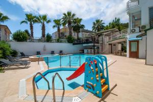 una piscina con scivolo in un cortile con palme di Fevkalade & Aparts Otel a Kemer