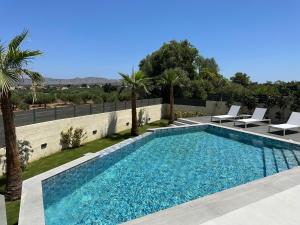 - une piscine avec 2 chaises longues et 2 palmiers dans l'établissement Kyamon Estate Luxury Villa, à Galangádhos