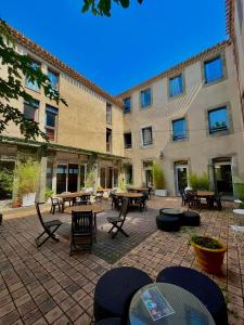 カルカソンヌにあるHostel Coeur de citéの建物の前のテーブルと椅子のあるパティオ