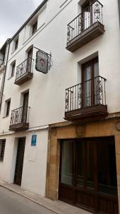 a white building with balconies and a clock on it at HOTEL FUENTE REDONDA LUXURY in Úbeda