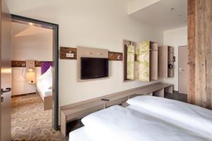 een hotelkamer met een bed en een spiegel bij Explorer Hotel Bad Kleinkirchheim in Bad Kleinkirchheim