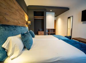 Un dormitorio con una gran cama blanca con almohadas azules. en Hotel Familia Conde, en Huelva 37 fotos más