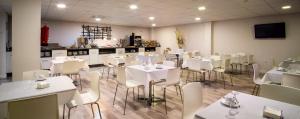 Un comedor con mesas blancas y sillas blancas. en Hotel Familia Conde, en Huelva