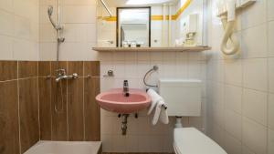 La salle de bains est pourvue d'un lavabo rose et de toilettes. dans l'établissement Hotel Bellevue, aux lacs de Plitvice