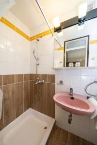 La salle de bains est pourvue d'un lavabo rose et d'une baignoire. dans l'établissement Hotel Bellevue, aux lacs de Plitvice