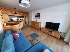 uma sala de estar com um sofá azul e uma televisão em Schwarzeck34 em Bachwinkl