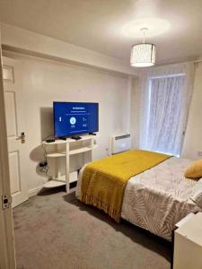 a bedroom with a bed and a flat screen tv at Modern two bedroom flat in North Stifford