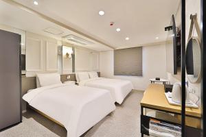 ein Hotelzimmer mit 2 Betten und einem TV in der Unterkunft Hotel Rubato Ulsan Jung-gu Haksung in Ulsan