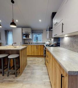 a large kitchen with wooden cabinets and a counter top at Presthaven Resort Haven Luxury 2023 Caravan in Prestatyn +8 photos