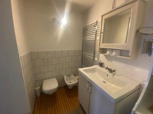 La salle de bains blanche est pourvue d'un lavabo et de toilettes. dans l'établissement I Bravi, à Malgrate