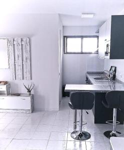eine weiße Küche mit 2 Stühlen und einer Theke in der Unterkunft Playaelporis in Poris de Abona