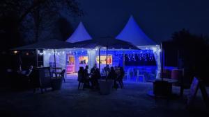 eine Gruppe von Menschen, die nachts unter Sonnenschirmen an Tischen sitzen in der Unterkunft camping les rives du lac in Bois Morin