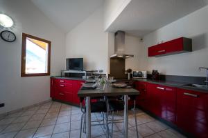 a kitchen with red cabinets and a table in it at appartement proche lac d'Annecy in Faverges