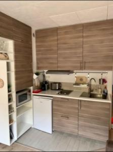 - une cuisine avec des placards en bois et un réfrigérateur blanc dans l'établissement Studio la Foux, à Allos