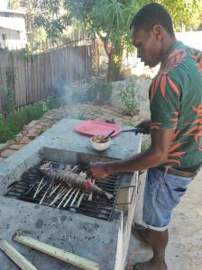 a man is cooking food on a grill at Villa Ilo Komba in Nosy Komba