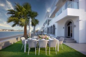 a dining table and chairs on a lawn next to the ocean at Villa Mallorca - Exclusive 11-Bedroom Villa with signature Amenities By Luxury Explorers Collection in Dubai