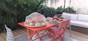 a red table with a bowl of fruit on a patio at Le RELAIS DE LEZAT in Lézat-sur-Lèze