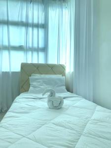 a white stuffed swan sitting on a white bed at Adel Homestay in Papar