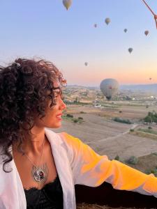 a woman is looking at a hot air balloon at Gedik Cave Hotel in Göreme