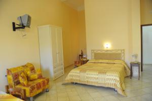 una camera con letto, sedia e TV di il Giardino degli Agrumi a Custonaci
